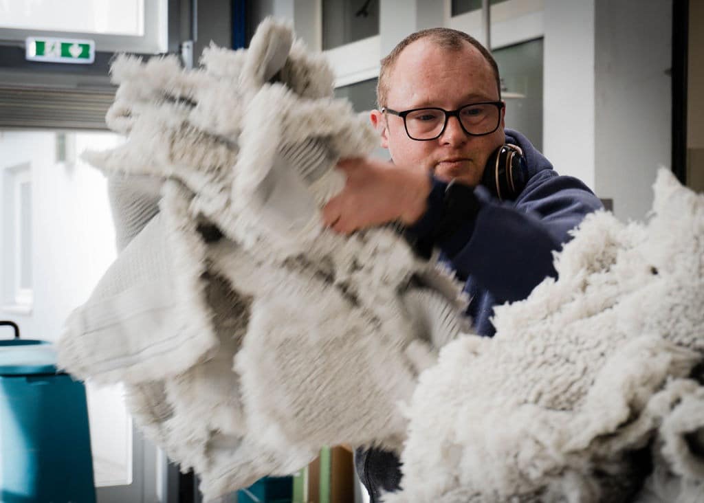 Ein junger Mann sortiert Wischmobs in der Kooperation mit EDER.