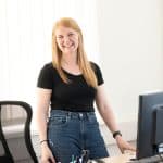 Eine BIGS Coachin steht in einem Raum und lächelt offen.