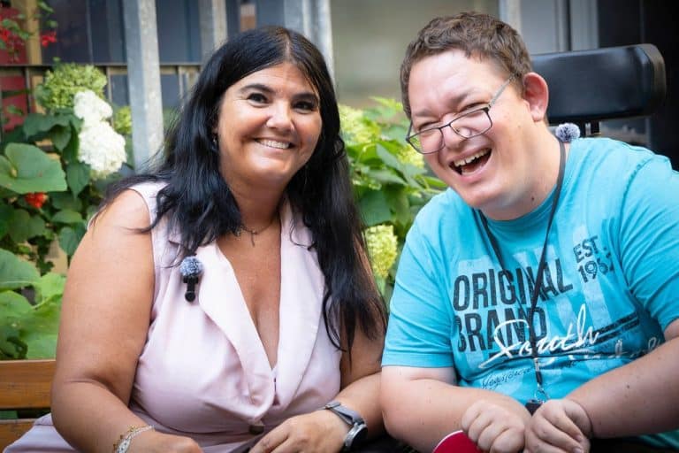 Zwei Menschen sitzen nebeneinander und lachen