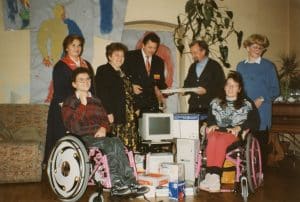 Ein historisches Foto einer Spendengabe die den Verein gegeben wurde. In der mitte sieht man einen Röhren-Bildshcirm und andere verpackte Geräte.