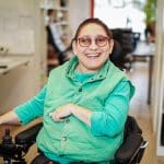 Eine Rollyfahrerin aus dem Digiprint arbeitet grinst in die Kamera.