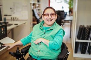 Eine Rollyfahrerin aus dem Digiprint arbeitet grinst in die Kamera.