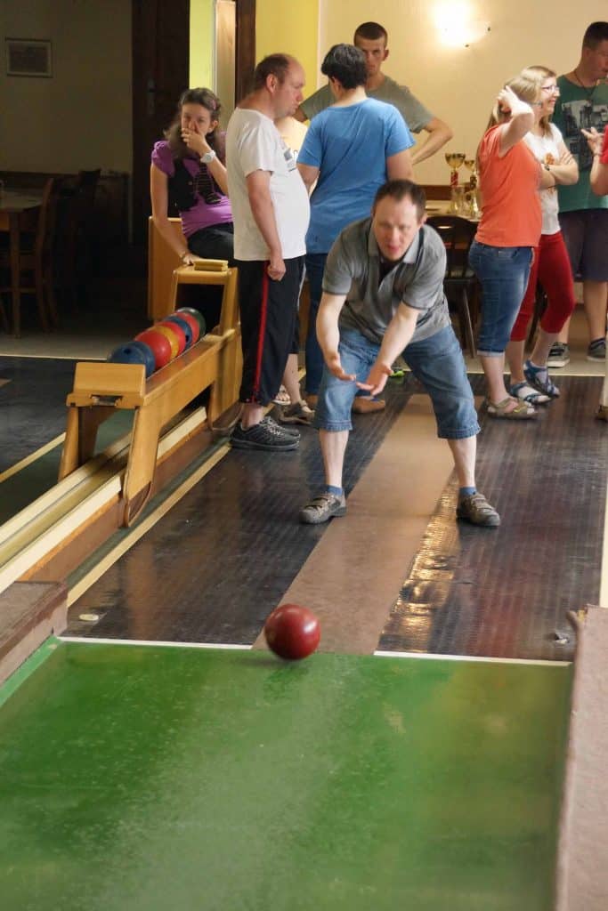Ein Mann rollt eine Bowlingkugel mit zwei Händen.