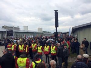 Eine Demonstration im KZ Mauthausen. Eine Gruppe Männer Steht mit einer Warnweste herum.