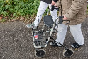 Ein Bild von eine älteren Dame die auf ihren Rollator angewiesen ist.