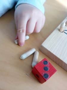 Eine Kleinkindhand das Holzdübel versucht zu nehmen.