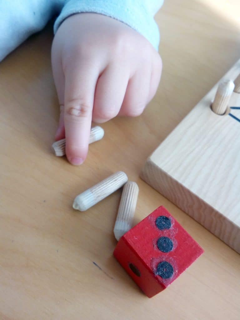 Eine Kleinkindhand das Holzdübel versucht zu nehmen.