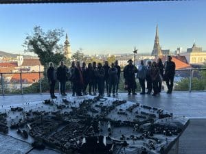 Ein Gruppenfoto neben einer Aussichtsplattform. Im Hintergrund sieht man die Dächer von Linz.