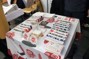 Ein Foto von dem Messestand auf der Connect in Linz. Am Tisch sieht man die Broschüren und Karten zum mitnehmen.