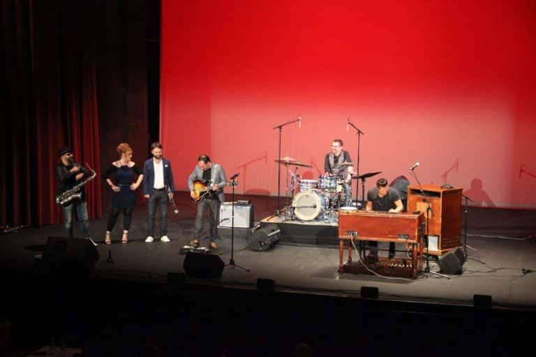 Auf der Bühne stehen die Musiker und lachen.