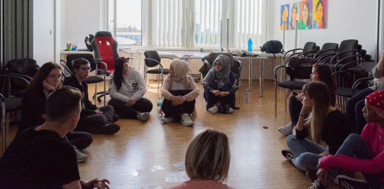 Einige Jugendliche vom Bigs sitzen gemeinsam im Kreis am Boden.