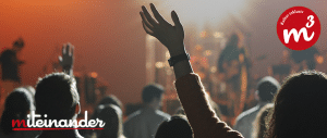 Banner von einem Konzert. Eine Frau streckt ihre Arme in die Luft.
