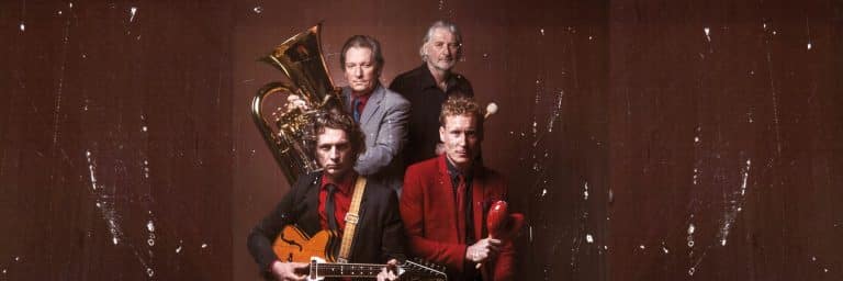 Ein Bandfoto von der Lettner Combo. Man sieht 4 Musiker mit ihren Instrumenten ausgerüstet voreinander stehen.