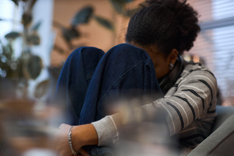 Eine Frau sitzt mit Depressionen am Boden.